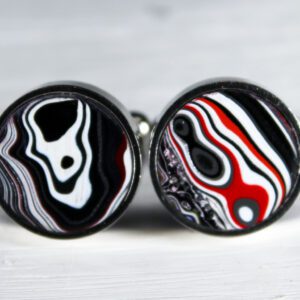 Round cufflinks with abstract black and red patterns.
