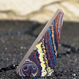 Polished triangular multicolored layered stone on black