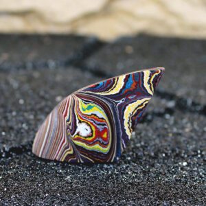 Colorful layered polished stone on dark sand