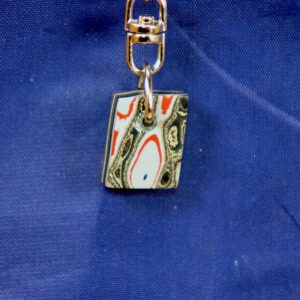 Colorful abstract rectangular pendant keychain on blue fabric