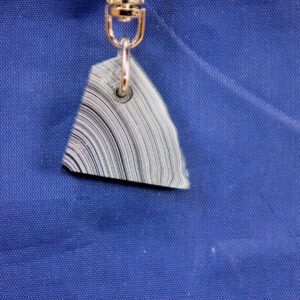 Triangular layered metal pendant keychain on blue
