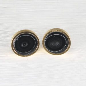 Two brass door peepholes on white surface
